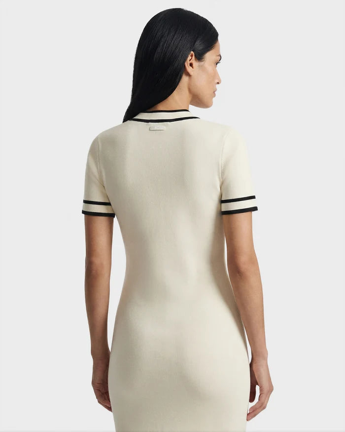 A woman with long, dark hair is shown from the back, wearing the Rudsak VINNIE - 8526038 Vanilla fitted knit midi dress with short sleeves and black trim, standing against a plain light background.