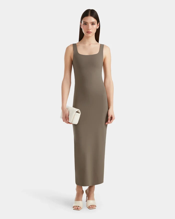A woman stands facing forward in the WANDA - 8524035 Cement women's maxi dress by Rudsak. The sleeveless, ankle-length style with a square neckline is paired with white heeled sandals and a clutch against a plain white background.