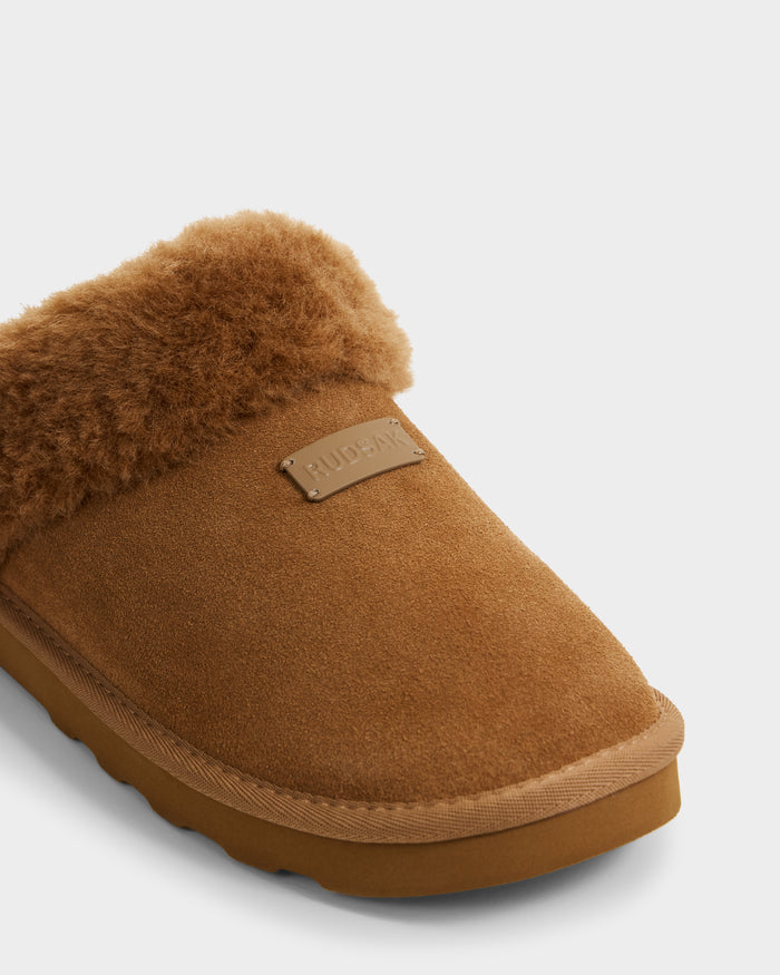A close-up of the Rudsak WILBER - 6225509 Tan men's suede slipper with a fluffy faux shearling lining, durable rubber sole, and a small embossed label on top—ideal for cozy at-home loungewear.