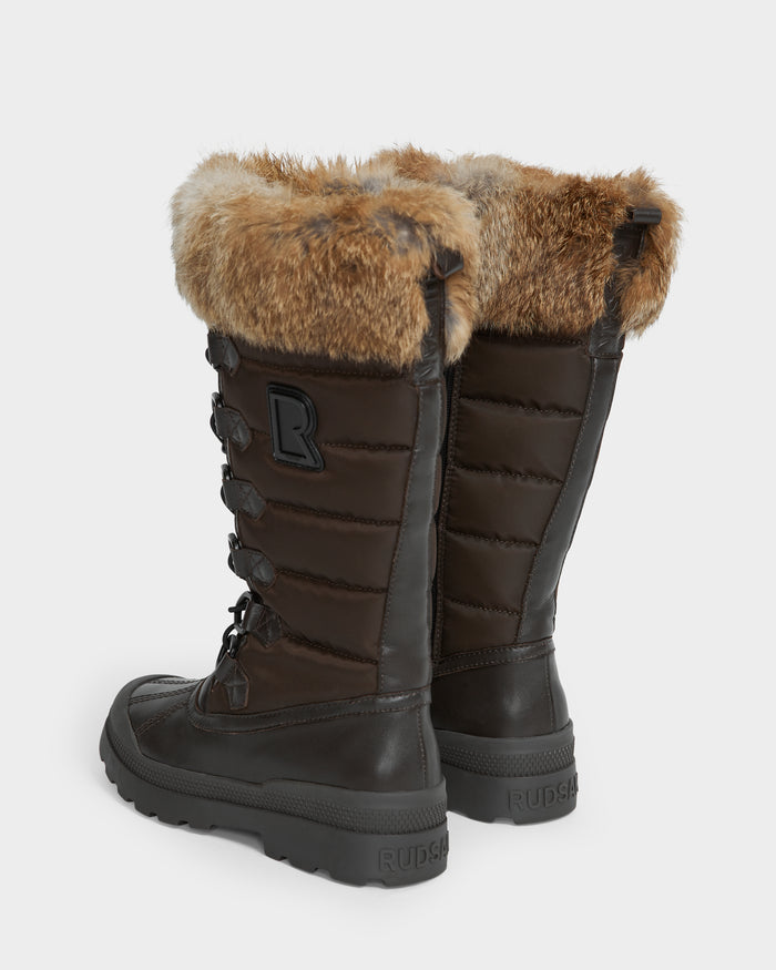 The Rudsak WINDY - L224507 Espresso women’s boots are tall, dark brown with faux fur trim, lace-up fronts, thick rubber soles for winter comfort, and feature a stylized R logo on the side.