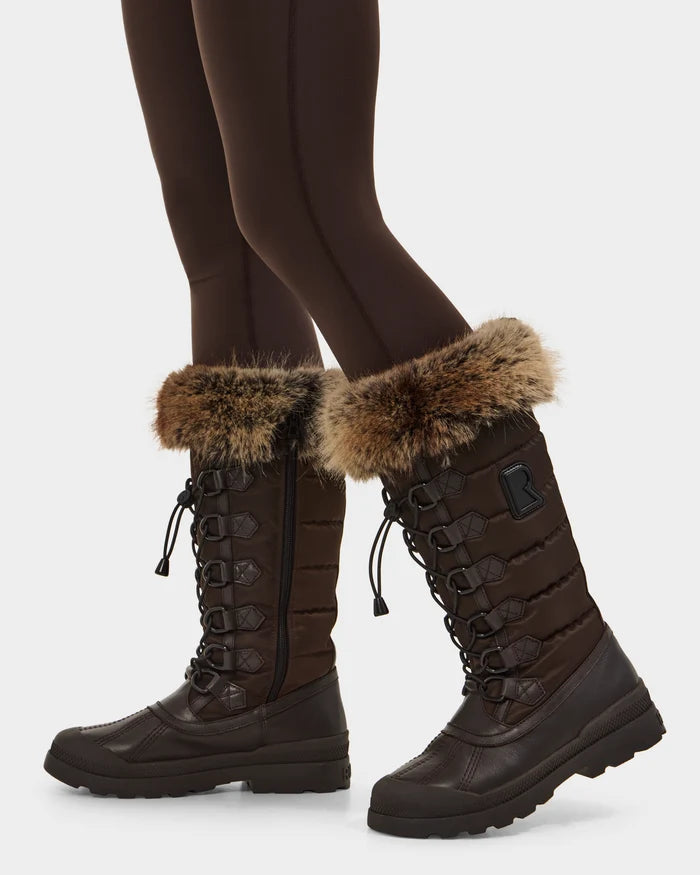 A person wears Rudsak’s WINDY - L224507 Espresso women’s winter boots with faux fur trim, laces, side zipper, and textured soles for comfort in cold weather, styled with leggings.