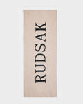 The Rudsak WYATT - 6425039 Vanilla is a beige rectangular towel featuring "RUDSAK" in bold black letters down the center—a stylish winter essential. The towel is showcased on a plain white background.
