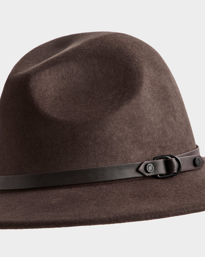 The ZELDA - 8425536 Espresso by Rudsak is a brown felted wool women’s fedora with a slightly indented crown, accented by a thin dark brown leather band and small buckle detail at the base.