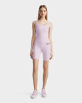 A young woman faces forward, wearing the Rudsak ZORA - 8524066 Lilac Foam fitted sleeveless bodysuit with matching high-performance biker shorts and lavender sneakers, set against a plain white background.
